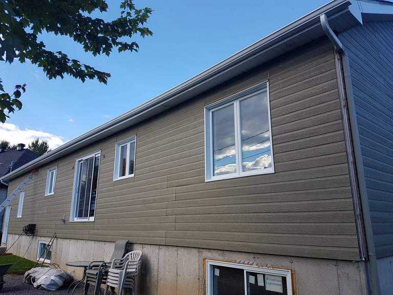 Home with taupe composite siding and a newly installed gray gutter along the roofline — Gouttières et Revêtements Synergy