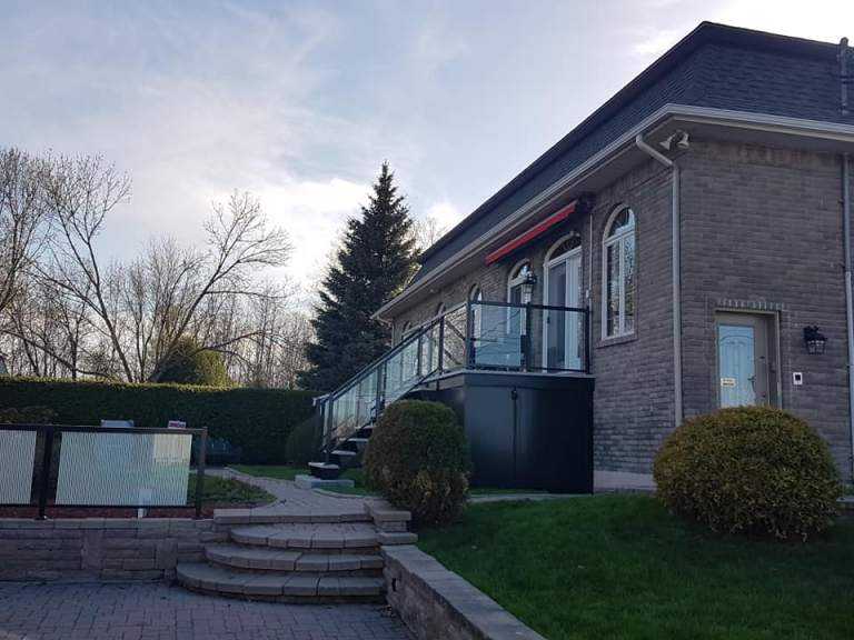 Résidence en brique beige au crépuscule avec gouttière et fascia blancs — Gouttières et Revêtements Synergy