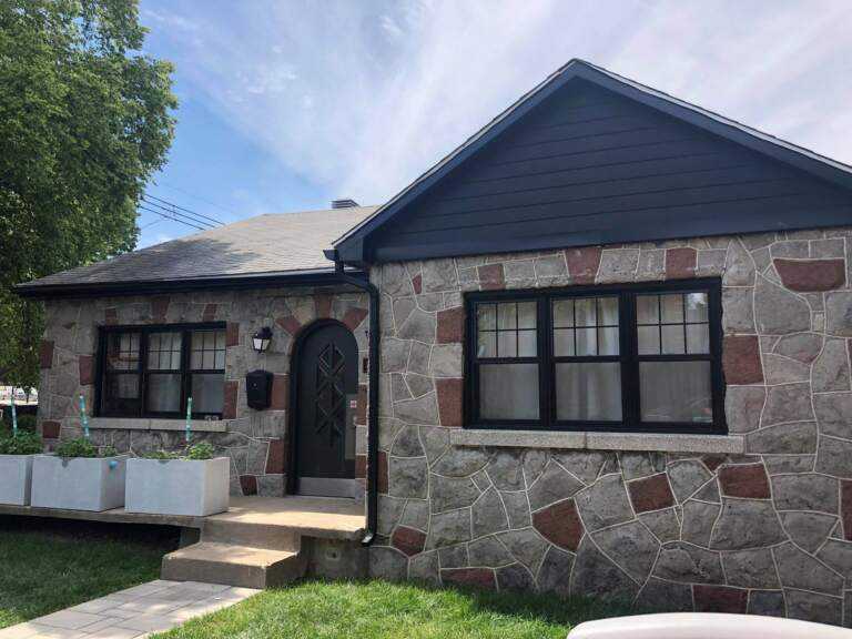 Maison en pierre avec gouttières en aluminium noir, soffite, fascia et déclin de pignon installés par Gouttières et Revêtements Synergy