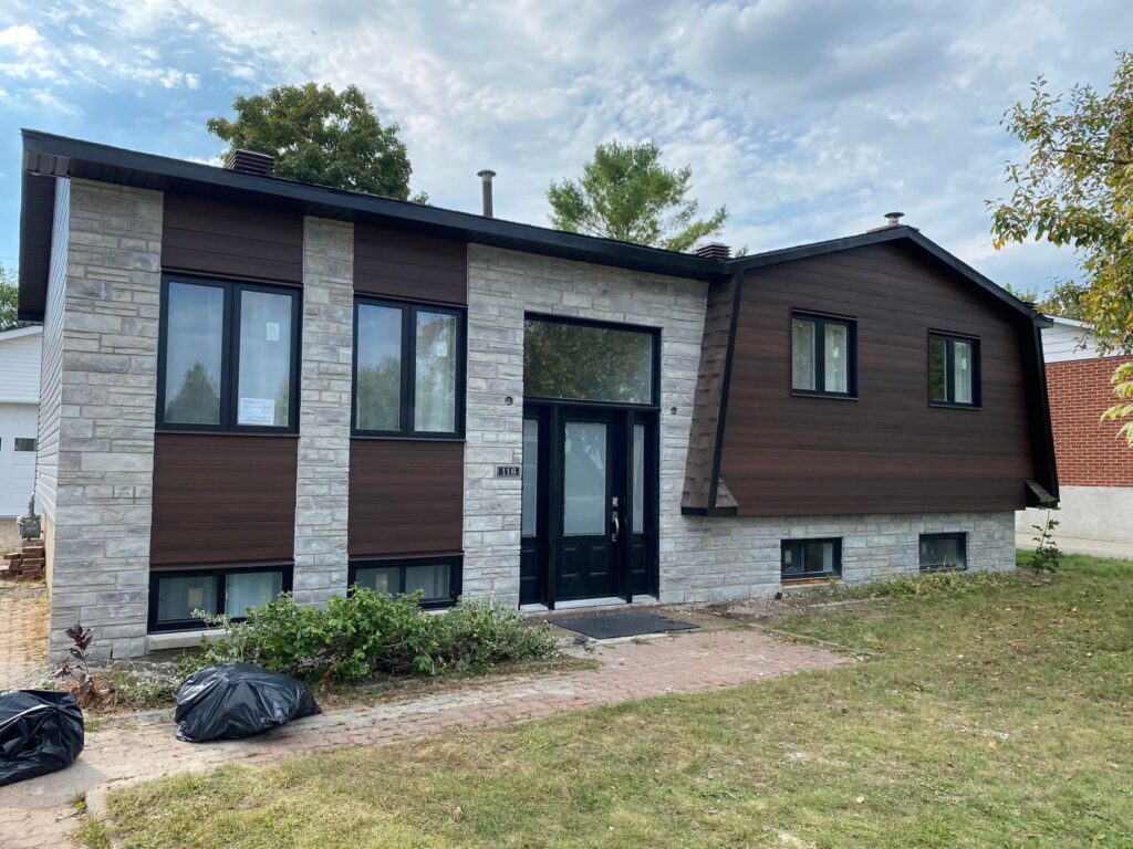 Bungalow surélevé, déclin horizontal brun et pierre grise, fascia et gouttière noirs — Gouttières et Revêtements Synergy