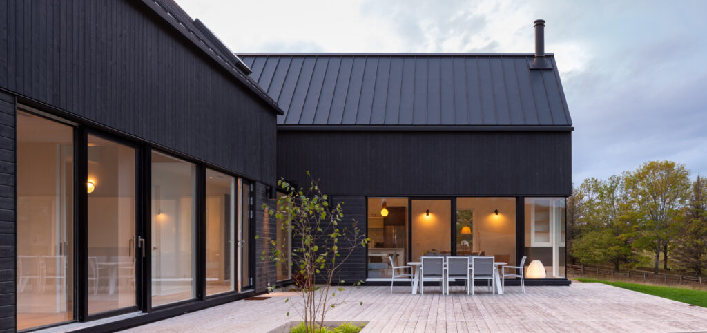 Maison contemporaine en déclin de bois vertical noir, toiture métallique à joints debout — Gouttières et Revêtements Synergy